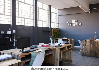 Modern business office interior containing tables and chairs, computers and office supplies with no employees