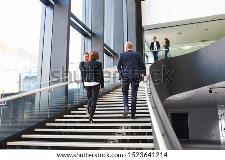 Modern business people walking on stairs in glass hall of office building