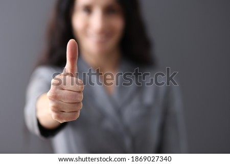 Modern business woman showing thumb up in office closeup. Successful deals concept