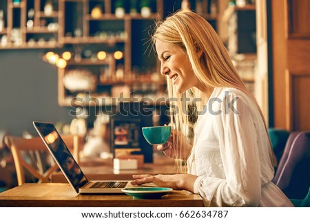 Modern business woman is using laptop in coffee shop.