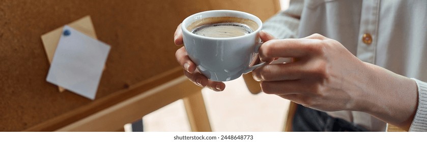 A modern businesswoman taking a coffee break in her office space, holding a cup of freshly brewed coffee in hand. - Powered by Shutterstock