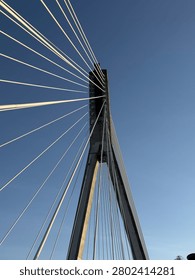 A modern cable-stayed bridge with geometric lines against a clear blue sky.