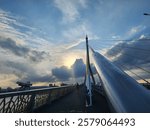 Modern cable-stayed bridge with striking geometric design at sunset. Golden light, dramatic clouds, and urban skyline create a captivating scene. Rama VIII Bridge, Beautiful bridge Bangkok Thailand.