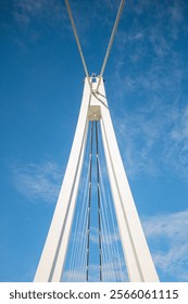 A modern cable-stayed bridge tower reaching into a clear blue sky.