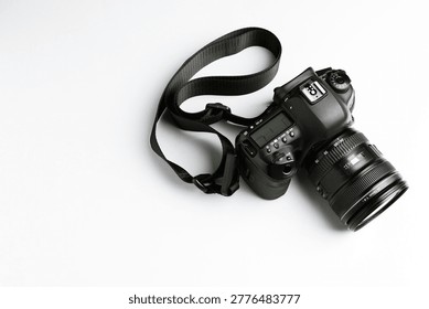 Modern camera with strap on light background, top view. Space for text