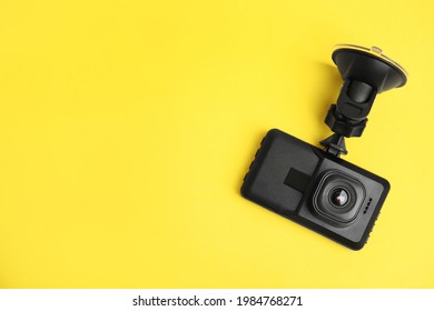 Modern car dashboard camera with suction mount on yellow background, top view. Space for text