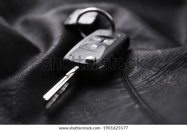 Modern car flip key with trinket on black\
leather, closeup