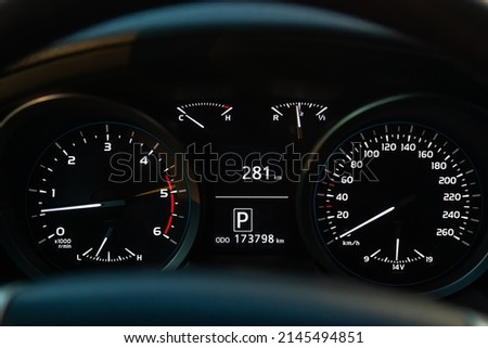 Modern car illuminated dashboard closeup. White arrows on Speedometer.