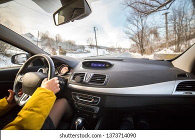 Modern Car Interior With Driver Female Hands On Steering Wheel, Winter Snowy Landscape Outside. Safe Driving Concept.