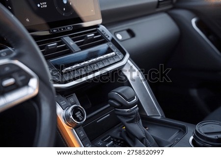 Modern car interior featuring a large floating touchscreen display with navigation, sleek air vents, and climate control buttons on a premium dashboard during sunset golden hour. High-tech cabin.
