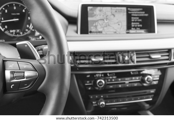 Modern car interior,\
red steering wheel with media phone control buttons,navigation,\
screen multimedia system background, car interior details. Black\
and white