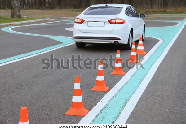 Modern car on driving school test track with\
traffic cones