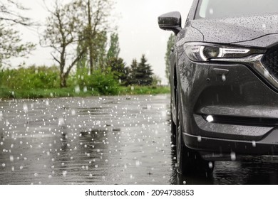 Modern car parked outdoors on rainy day with hail