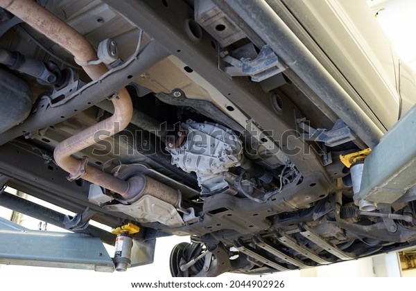 Modern car in a car service\
on a lift. Transfer case, muffler, exhaust pipe. Car service and\
repair.