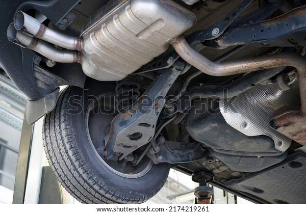 Modern car in a car service on a lift. Suspension\
elements and exhaust system. Auto parts and car service. Selected\
focus.