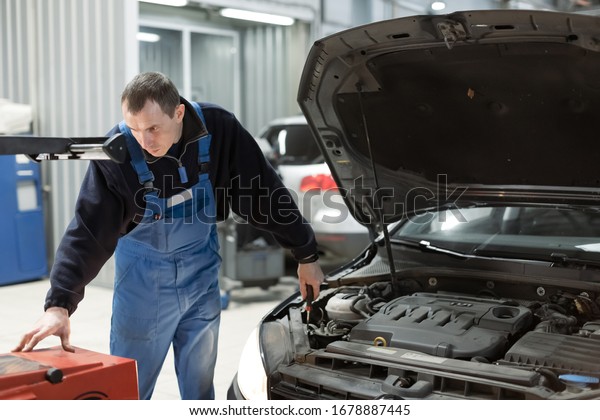 Modern car\
at a service station. Repairman is adjusting the headlight. He use\
special professional equipment. A photo shows a headlight sets\
process. Spare parts, service, repair\
concept.