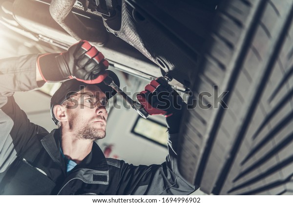 Modern Car\
Suspension Maintenance. Caucasian Automotive Technician in His 30s\
Fixing Vehicle Suspension Elements.\
