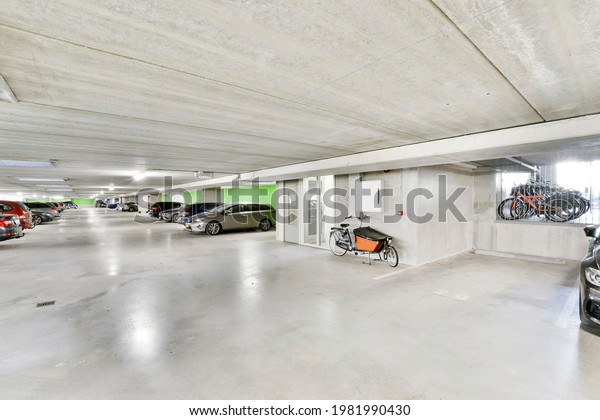 Modern cars and bicycles\
parked in spacious illuminated garage of contemporary apartment\
building