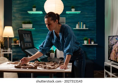 Modern caucasian engineer standing at table analyzing maquette layout building model plan for construction project. Architect woman designing professional renovation property view - Powered by Shutterstock