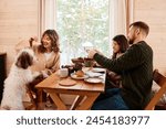 Modern Caucasian family with dog sitting at wooden table in country house enjoying tea party on winter day, copy space