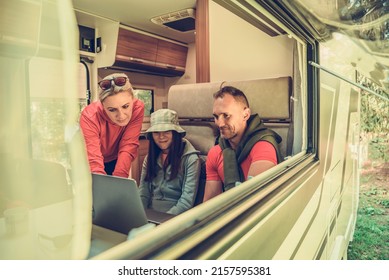 Modern Caucasian Family Of Three Having Fun Inside Their RV Motorhome Watching Funny Streaming Movies On A Laptop Computer. Summer Road Trip Theme.