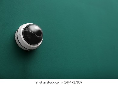 Modern CCTV security camera on green wall. Space for text