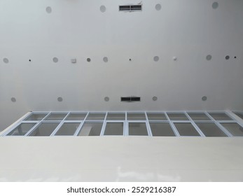 A modern ceiling with multiple circular lights and vents, viewed from below, showcasing a sleek, minimalist design