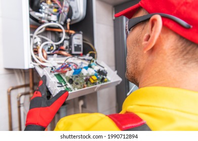 Modern Central Gas Heater Electronics Repair. Caucasian HVAC Technician Looking Inside The Heater. Industrial Theme.