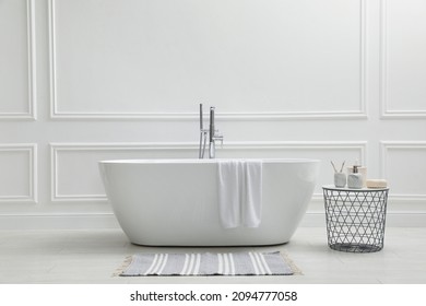 Modern ceramic bathtub and table with toiletries near white wall indoors - Shutterstock ID 2094777058