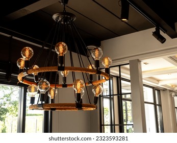 Modern chandelier in living room near glass window, loft style, vintage ceiling light or light bulbs hanging with from wooden ceiling, indoor, interior loft style building. Retro lighting decoration.