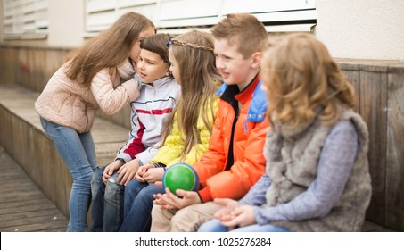 Modern Children On A Bench Playing Chinese Whispers