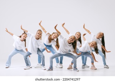 Modern choreography lesson. Dance group of happy, active little girls in jeans and t-shirts dancing isolated on white studio background. Concept of music, fashion, art, childhood, hobby. - Powered by Shutterstock