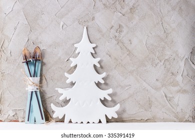 Modern Christmas Decor White Christmas Tree And Toy Wooden Ski With Gray Plastered Wall As Background. With Copy Space On Right