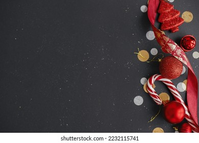 Modern christmas flat lay. Stylish christmas candy cane, confetti and red baubles border on black background. Season's greetings card, space for text. Merry Christmas! Winter holidays banner - Powered by Shutterstock