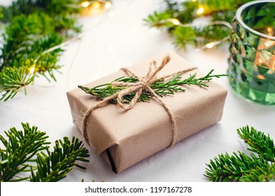 Modern Christmas wrapped presents with natural decor on white background. Gifts boxes in craft paper with twine and green branches. Merry Christmas concept. Seasonal greetings card. Happy holidays.