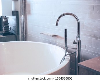 Modern Chrome Faucet On White Luxury Bath Tub In Bathroom. 