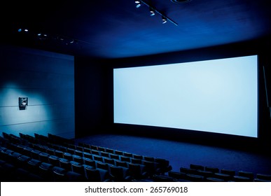 Modern Cinema Screen Auditorium With White Blank Screen And Luxury Seats - Dark Movie Theatre Ready For Projection - With Empty Rows Of Seats