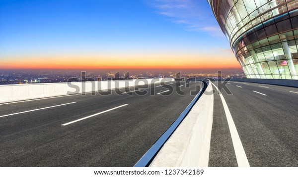 Modern city skyline and buildings with empty\
asphalt road at night