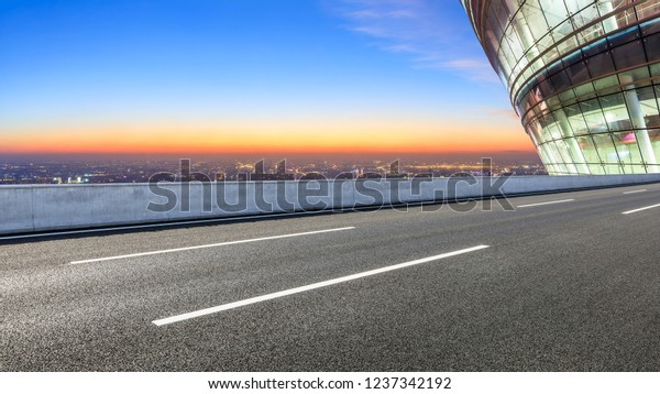 Modern city skyline and buildings with empty\
asphalt road at night