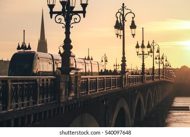 Modern City Tram On Pont De Pierre Bridge In Bordeaux At Sunset