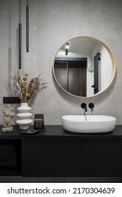 Modern classic design in bathroom with stylish decorations, big round mirror over oval, white washbasin in simple, black cabinet - Shutterstock ID 2170304639