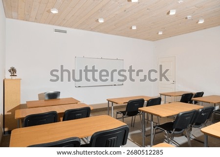 The modern classroom setup features a spacious layout with desks and a large whiteboard