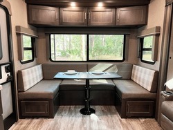 Modern, Clean Design Of A Fifth Wheel Travel Trailer Shows The Dining Area With Storage And A Huge Picture Window.