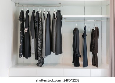 Modern Closet With Row Of Black Dress Hanging On Coat Hanger In Wardrobe.