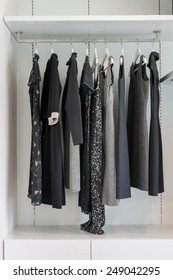 Modern Closet With Row Of Black Dress Hanging On Coat Hanger In Wardrobe.