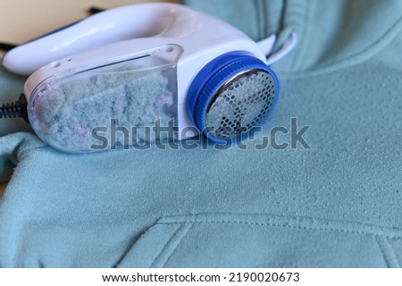 Modern cloth razor with full tank on clothes, space for text. View from above.
