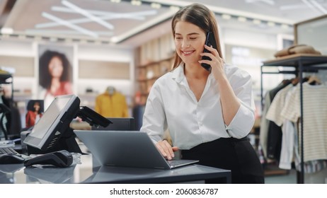 Modern Clothing Store: Friendly Customer Support Specialist Talks To Client On The Smartphone. Smiling Retail Sales Manager Or Young Designer Contacts Client About Online Order In Fashion Shop