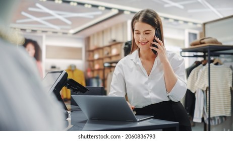 Modern Clothing Store: Friendly Customer Support Specialist Talks To Client On The Smartphone. Smiling Retail Sales Manager Or Young Designer Contacts Client About Online Order In Fashion Shop