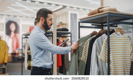 Modern Clothing Store: Male Visual Merchandising Professional Uses Digital Tablet Computer To Create New Collection Strategy. Fashionable Shop Sales Retail Associate Orders Stylish New Stock Items