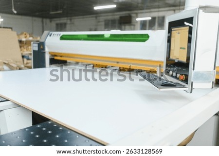Modern cnc machine cutting a large white wood panel in a furniture factory, showcasing advanced manufacturing processes